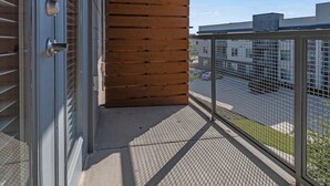 Ein Balkon mit einer Holzlamellenwand, einem Metallgeländer und freiem Blick auf die umliegenden Gebäude.