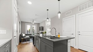 A modern kitchen with grey cabinets, a central island, and pendant lighting. - Sleeps 10 w/King Bed+Gym+Free Parking+Stockyards (Fort Worth)