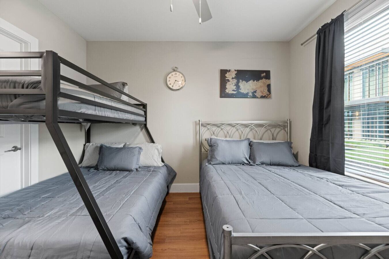Ein Schlafzimmer mit Etagenbetten, einer Wanduhr, einem Gemälde und einem Fenster mit Vorhängen.