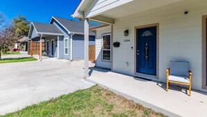 A residential house with a blue door, a number 1206 sign, and a wooden bench outside.