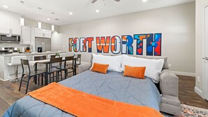 A modern bedroom with a large bed, a desk, and a kitchenette.