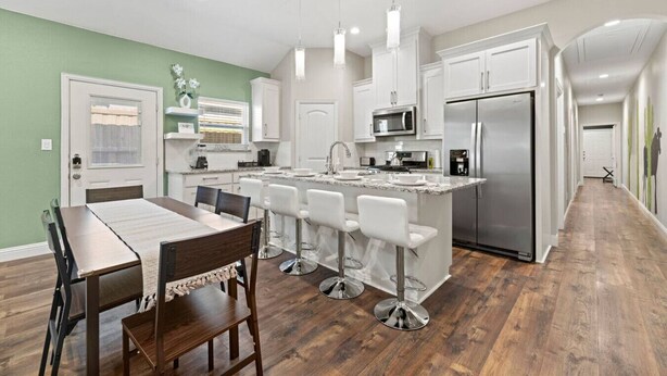 A modern kitchen with white cabinets, stainless steel appliances, and a central island with bar stools.