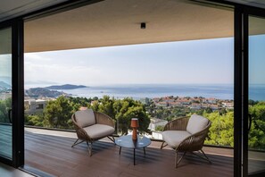A balcony with two wicker chairs, a small round table, and a wine glass. - Modern Villa in Dubrovnik with Infinity Rooftop Pool (Dubrovnik)