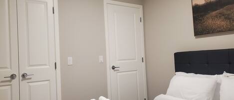 Une chambre d’hôtel avec un lit, deux portes blanches et un tableau au mur.