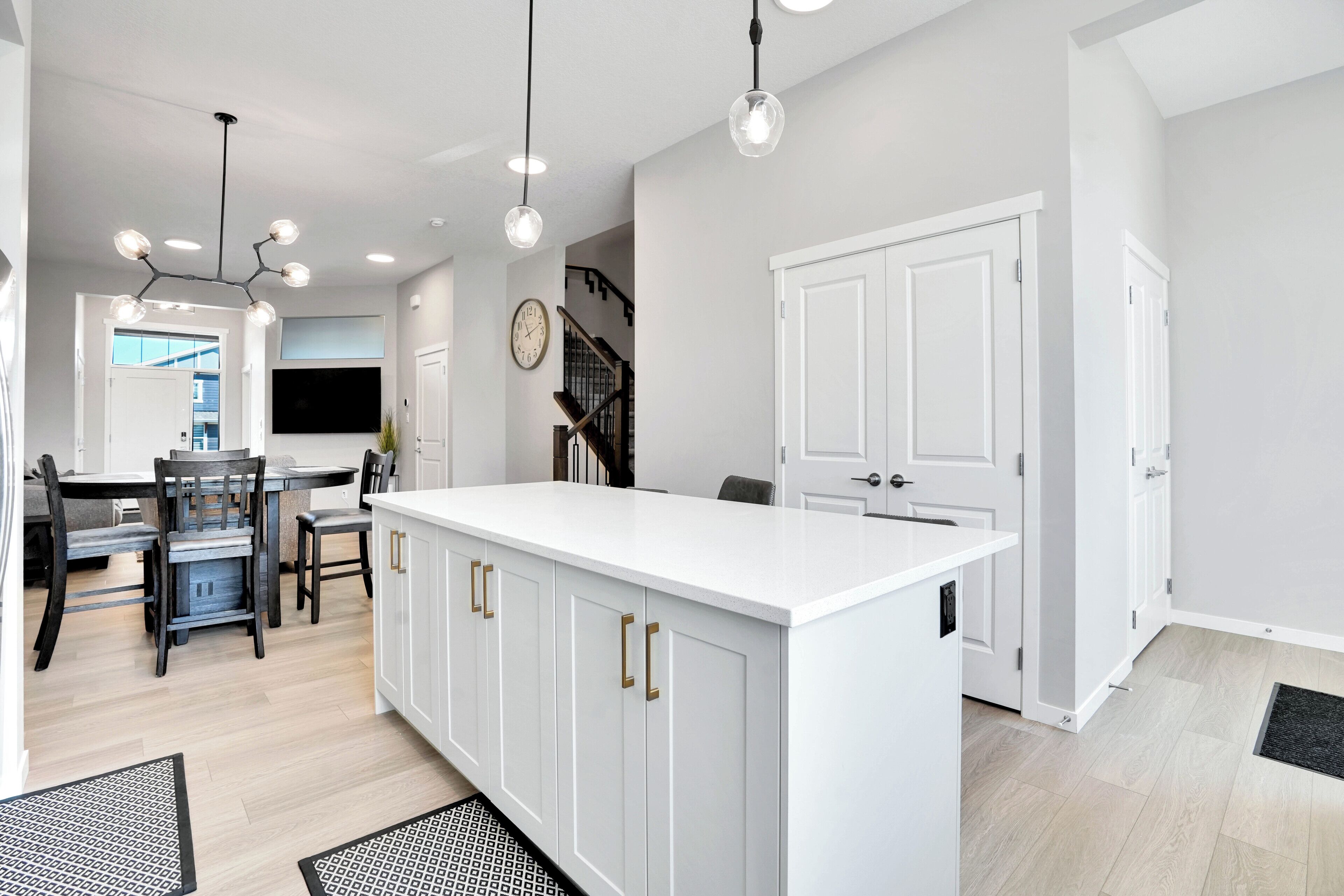 Una cocina moderna con armarios blancos, una isla central e iluminación colgante.