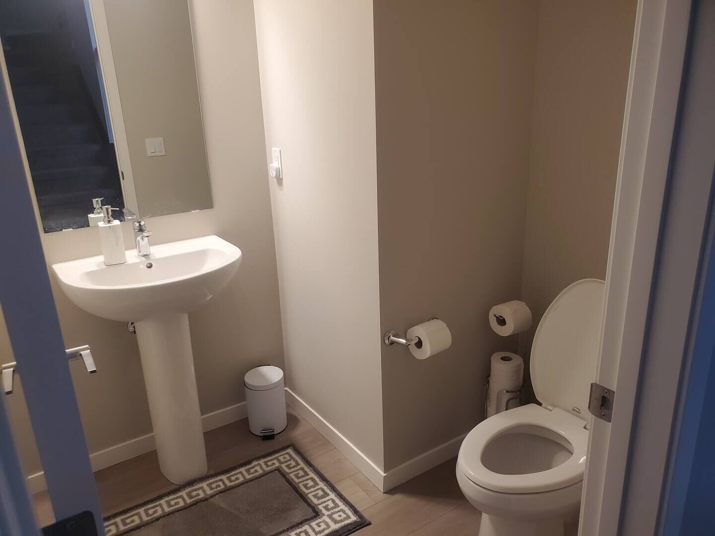 Ein kleines Badezimmer mit einem weißen Waschbecken, einer Toilette und einem Mülleimer.