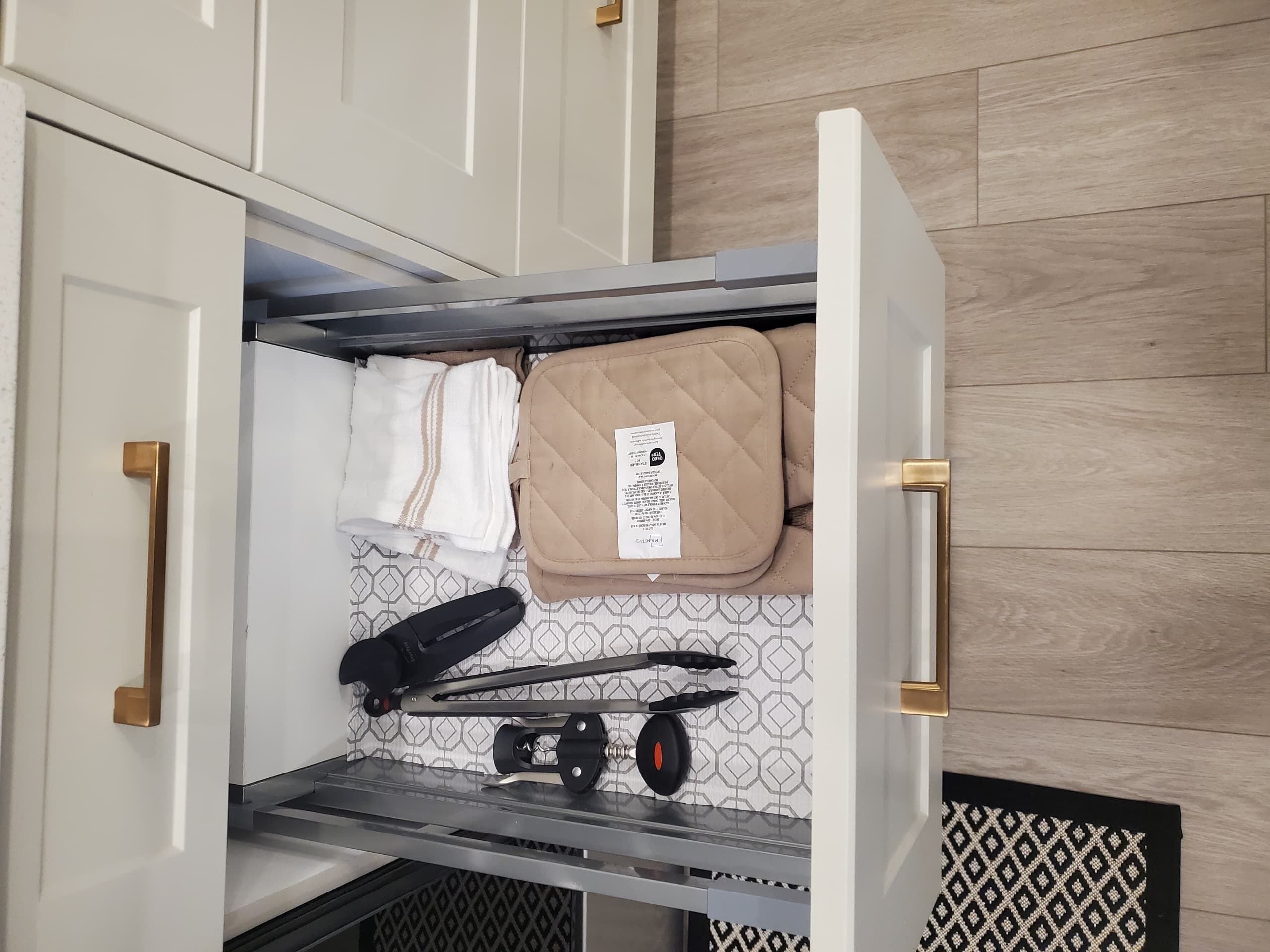 Un compartiment de rangement contenant une serviette pliée, un sac matelassé et une paire d’écouteurs.