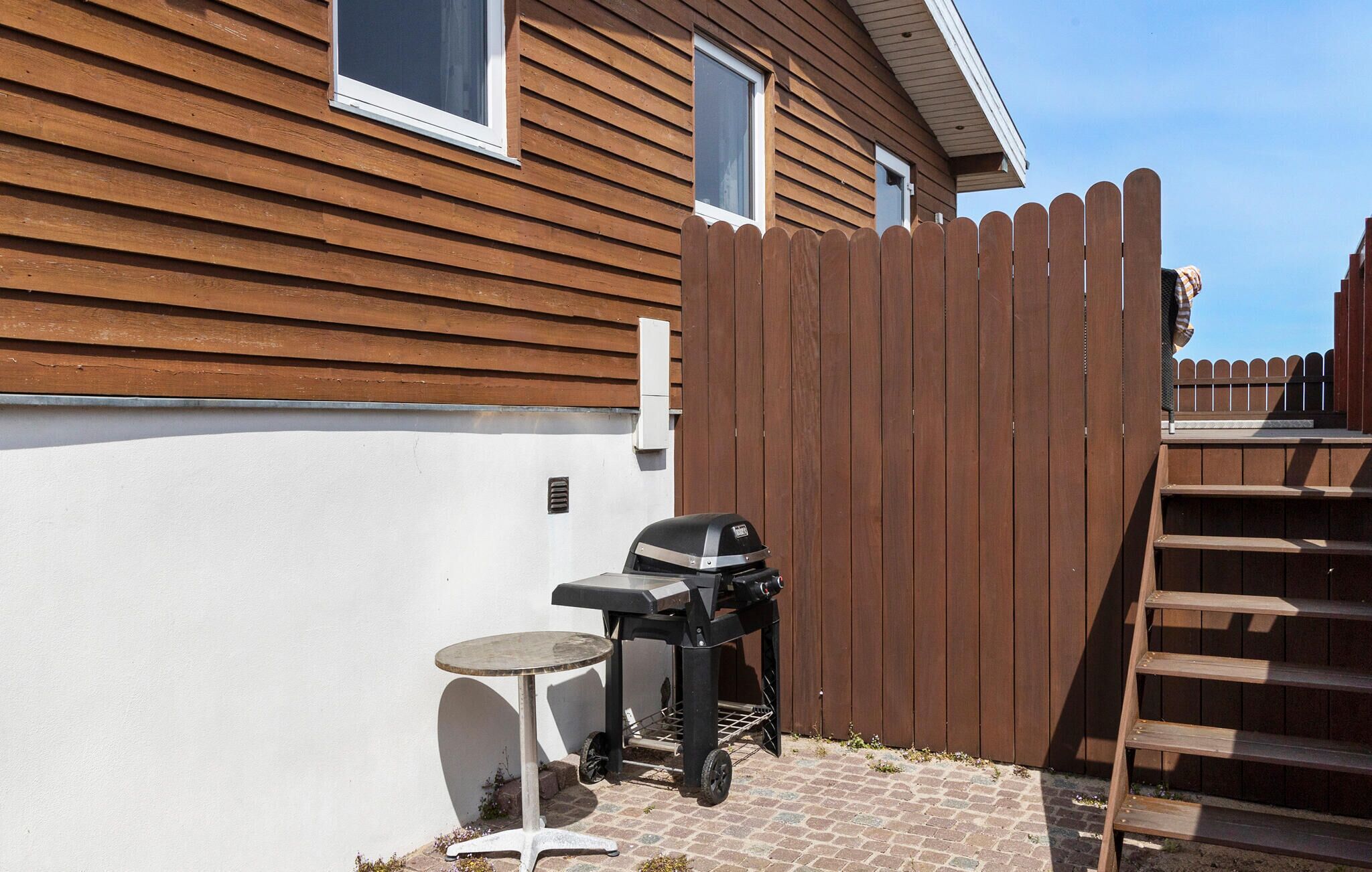 Ein Garten mit Holzzaun, Grill und einem kleinen Tisch.