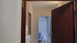 A hallway with a door leading to a room. A light switch is visible on the wall. - La Frégate Town Centre and Beach (Le Grau-du-Roi)