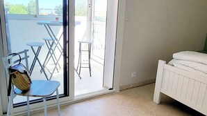 A room with a bed, a chair, and a table on a balcony with a view. - La Frégate Town Centre and Beach (Le Grau-du-Roi)