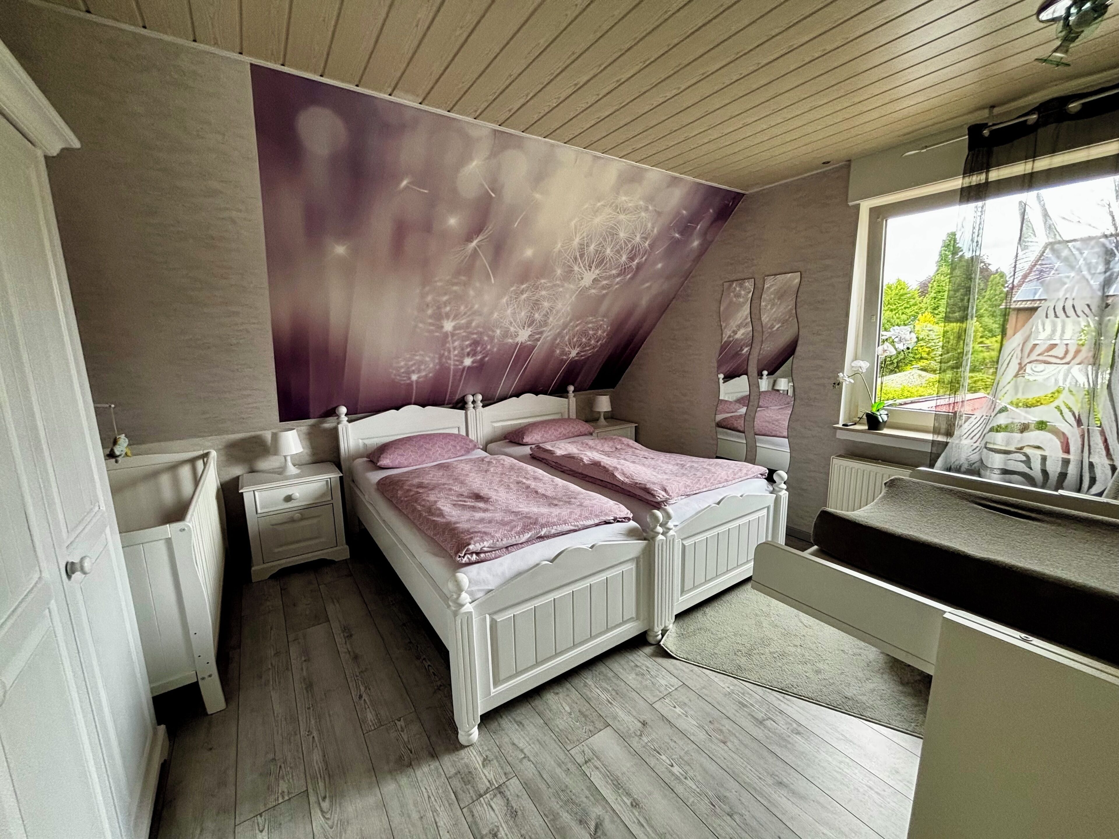 Een slaapkamer met een groot bed, twee nachtkastjes, een raam met uitzicht op groen en een plafond met een leeuwendanspatroon.