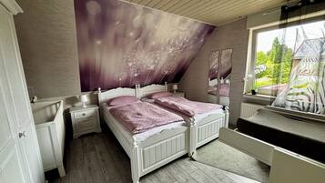 Een slaapkamer met een groot bed, twee nachtkastjes, een raam met uitzicht op groen en een plafond met een leeuwendanspatroon.