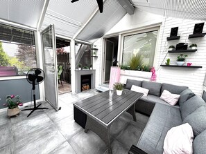 An outdoor patio with a sofa, a table, and a fan. - Family-friendly vacation apartment close to the city and the river Hase. (Haselünne)