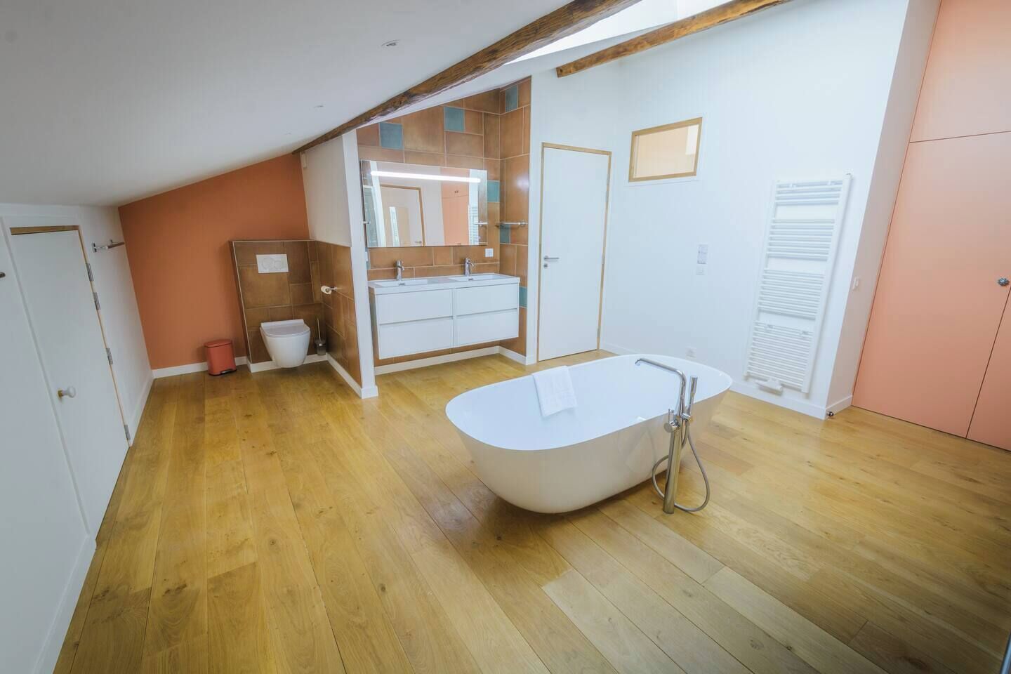 A modern bathroom with a freestanding bathtub, a vanity with a mirror, and a shower area.