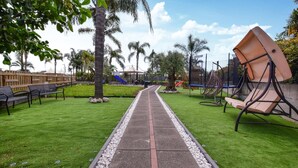 Un percorso che si snoda attraverso un parco, con panchine, altalene e un’area giochi.