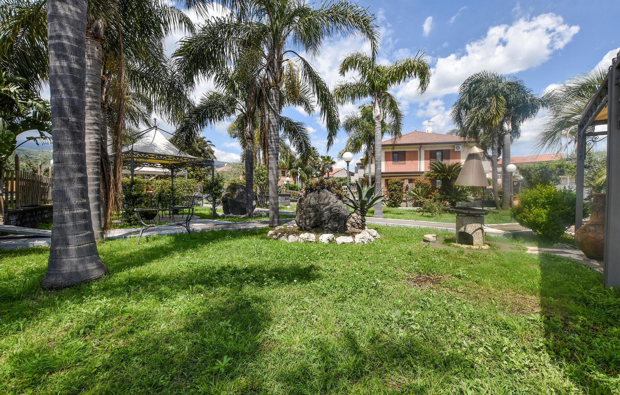 Un giardino curato con palme, un gazebo e una struttura in pietra.