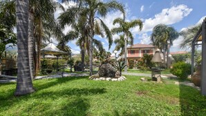 Un giardino curato con palme, un gazebo e una struttura in pietra.