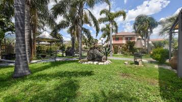 Un giardino curato con palme, un gazebo e una struttura in pietra.