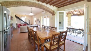 A spacious kitchen with a wooden dining table and chairs, a staircase leading to a loft, and a view of the outdoors. - Stunning home in Lucignano (Lucignano)