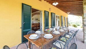 A long wooden table set for dining with chairs, green shutters, and a brick floor. - Stunning home in Lucignano (Lucignano)