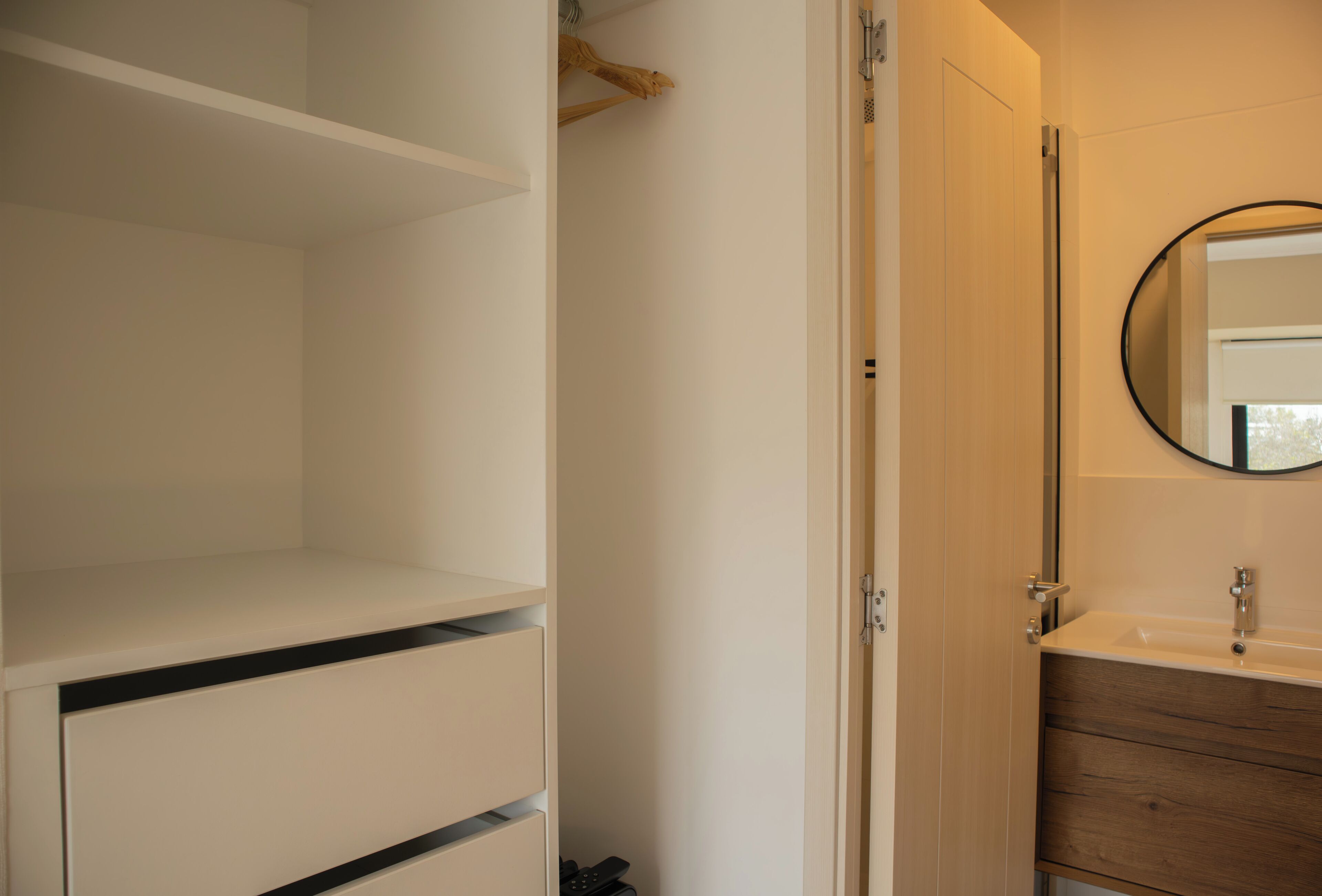 A bathroom with a white vanity, a wooden cabinet, and a mirror.