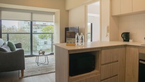 Una cocina moderna con microondas integrado, cafetera y una mesita con botellas.