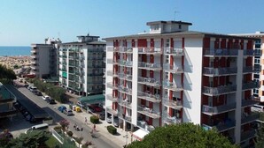 A multi-story hotel with balconies, a parking area, and a view of the beach.