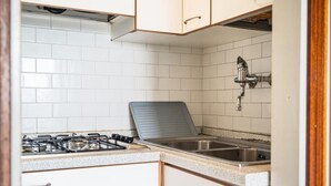 A kitchen with white cabinets, a gas stove, a sink, and a backsplash.