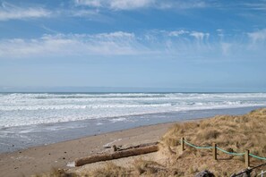 A beach with waves, a sandy shore, and a rope barrier. - Remodeled Oceanfront Suite - Indoor Pool and Ocean Views! (Lincoln City)