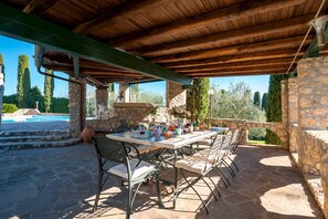 Eine Terrasse im Freien mit Steinmauern, einem Pool und einem Essplatz.