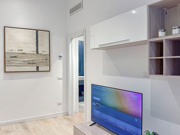 A modern living room with a large flat-screen TV, a framed abstract painting, and built-in shelving. - Santa Croce Suite - 10 mins from Duomo (Milano)