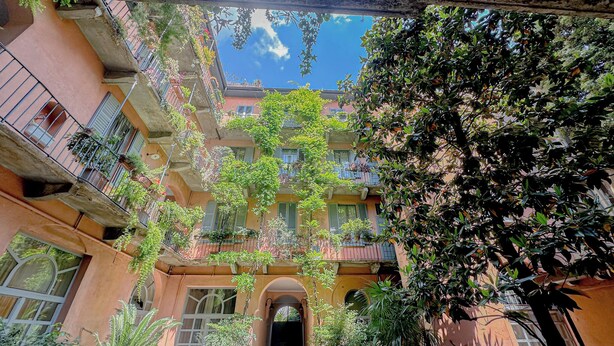 Une cour dotée de nombreux balcons, de plantes en pot et offrant une vue dégagée sur le ciel.