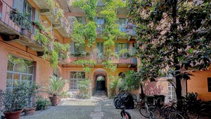 Une cour avec un chemin pavé, des plantes en pot, des vélos et un bâtiment doté de balcons.