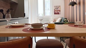 A modern dining area with a wooden table, chairs, and a kitchen in the background.