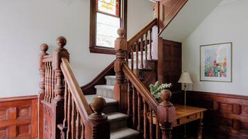 Un escalier en bois avec une rampe, une petite table et une lampe fixée au mur.