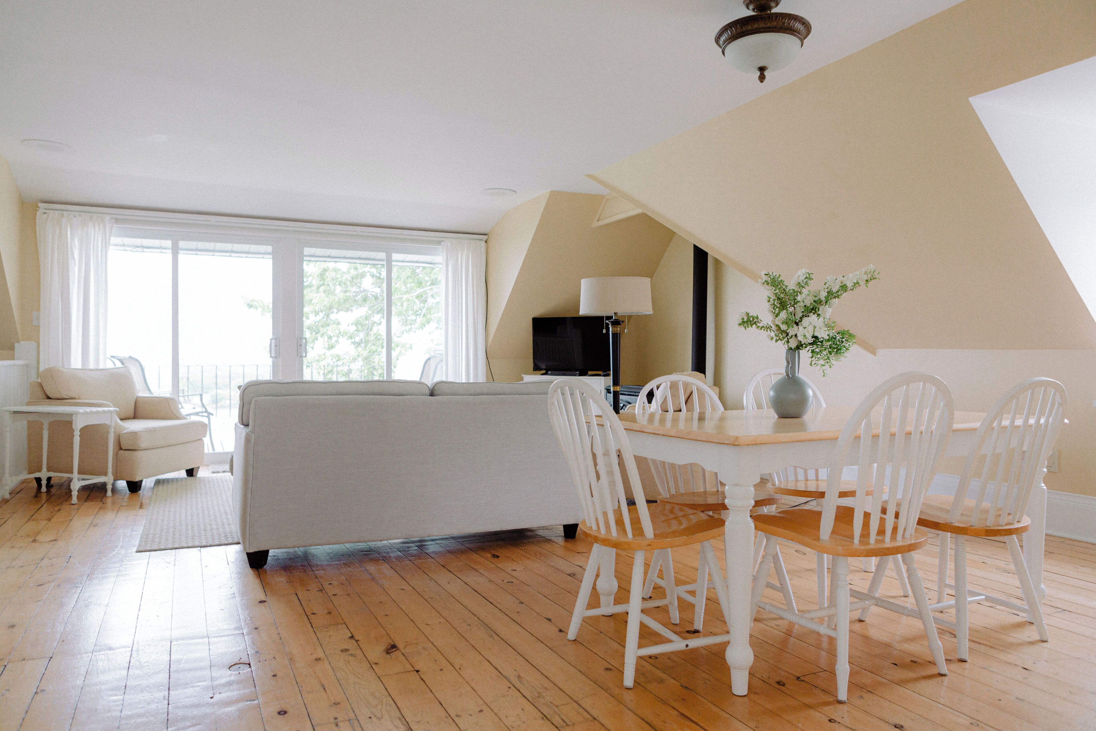 Un salon spacieux comprenant un canapé, une table à manger avec des chaises et une grande fenêtre laissant entrer la lumière naturelle.