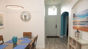 A dining area with a wooden table and chairs, a blue vase, and a chandelier.