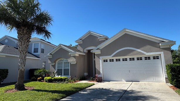 A residential house with a garage, a well-maintained lawn, and a palm tree.