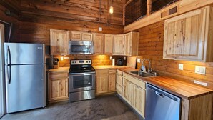 A kitchen with wooden cabinets, stainless steel appliances, and a concrete floor.