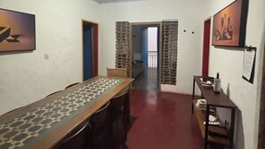 A room with a long table, a small seating area, and a door leading to another room. - Pousada Casa Matriz (Itabirito)