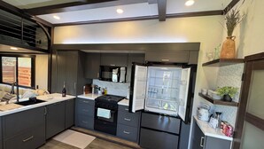 A modern kitchen with dark cabinetry, a stainless steel refrigerator, and a built-in oven.