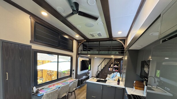 A compact kitchen with a dining area, a built-in stove, and a ceiling fan.