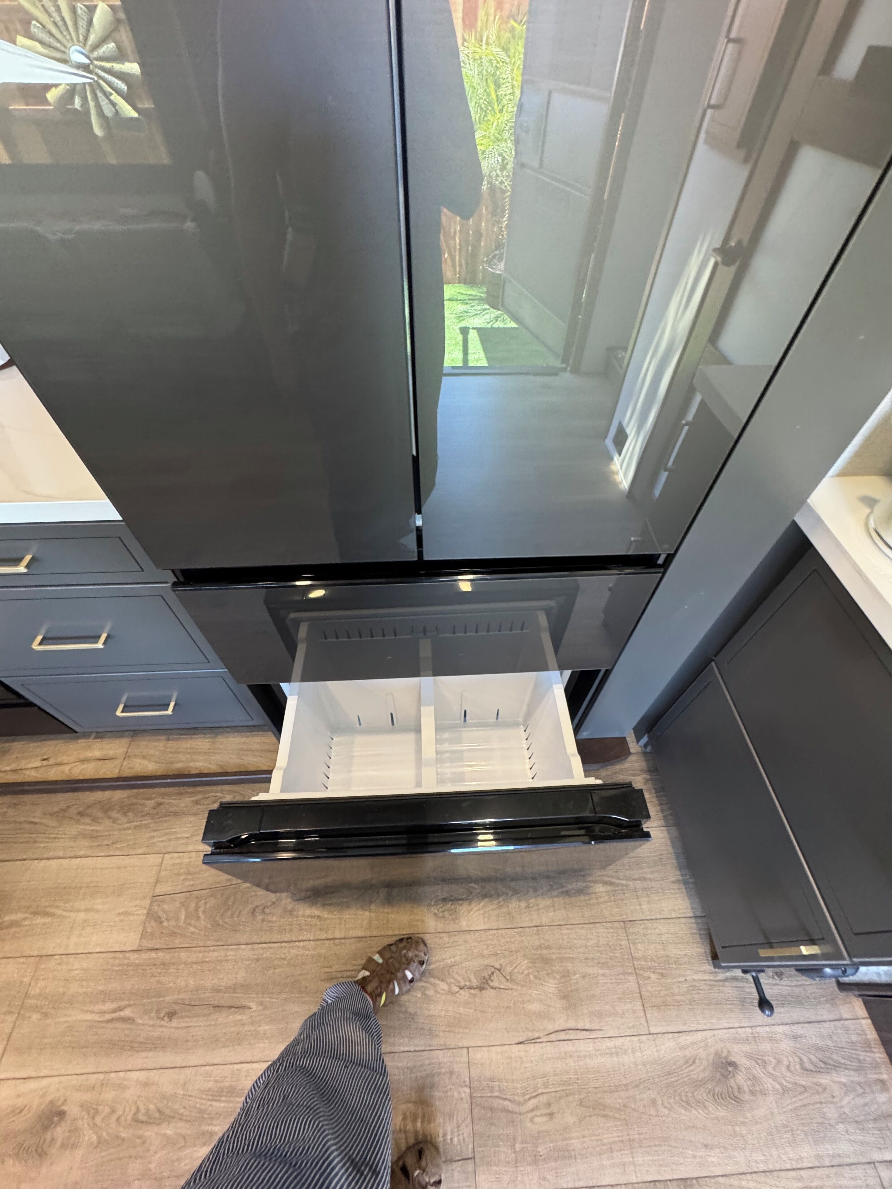 A kitchen with a black refrigerator, a stainless steel range hood, and a wooden floor.