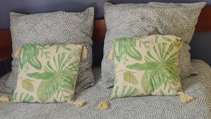 Una cama con una colcha estampada y dos almohadas con diseño de hojas.