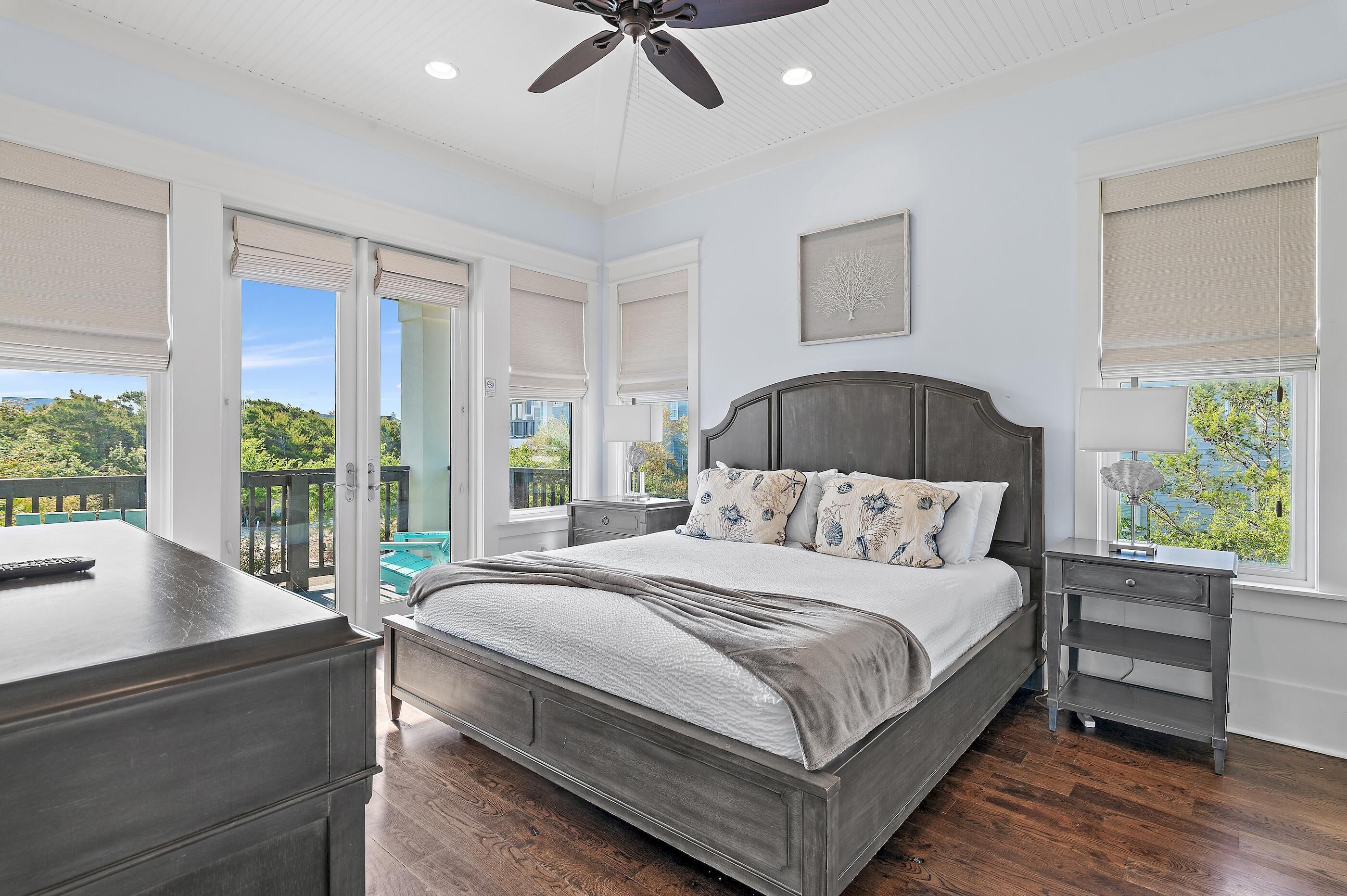 A bedroom with a bed, nightstands, a desk, and a ceiling fan.