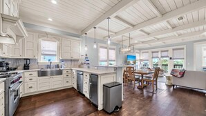 A spacious kitchen with white cabinetry, a stainless steel sink, and a wooden dining area. - Inlet Beach Retreat 202 (Panama City Beach)