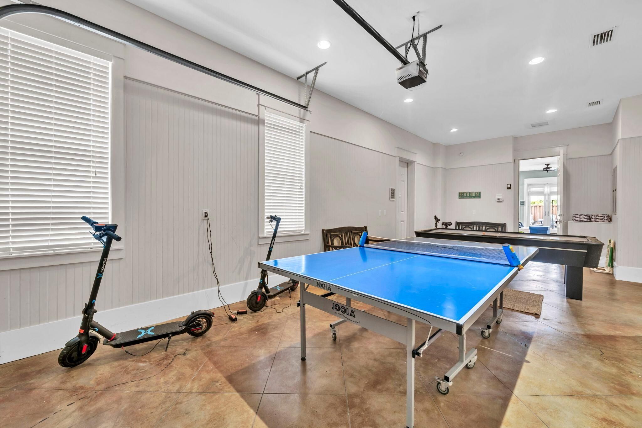 Una habitación amplia con mesa de ping pong, una patineta y mesa de billar.