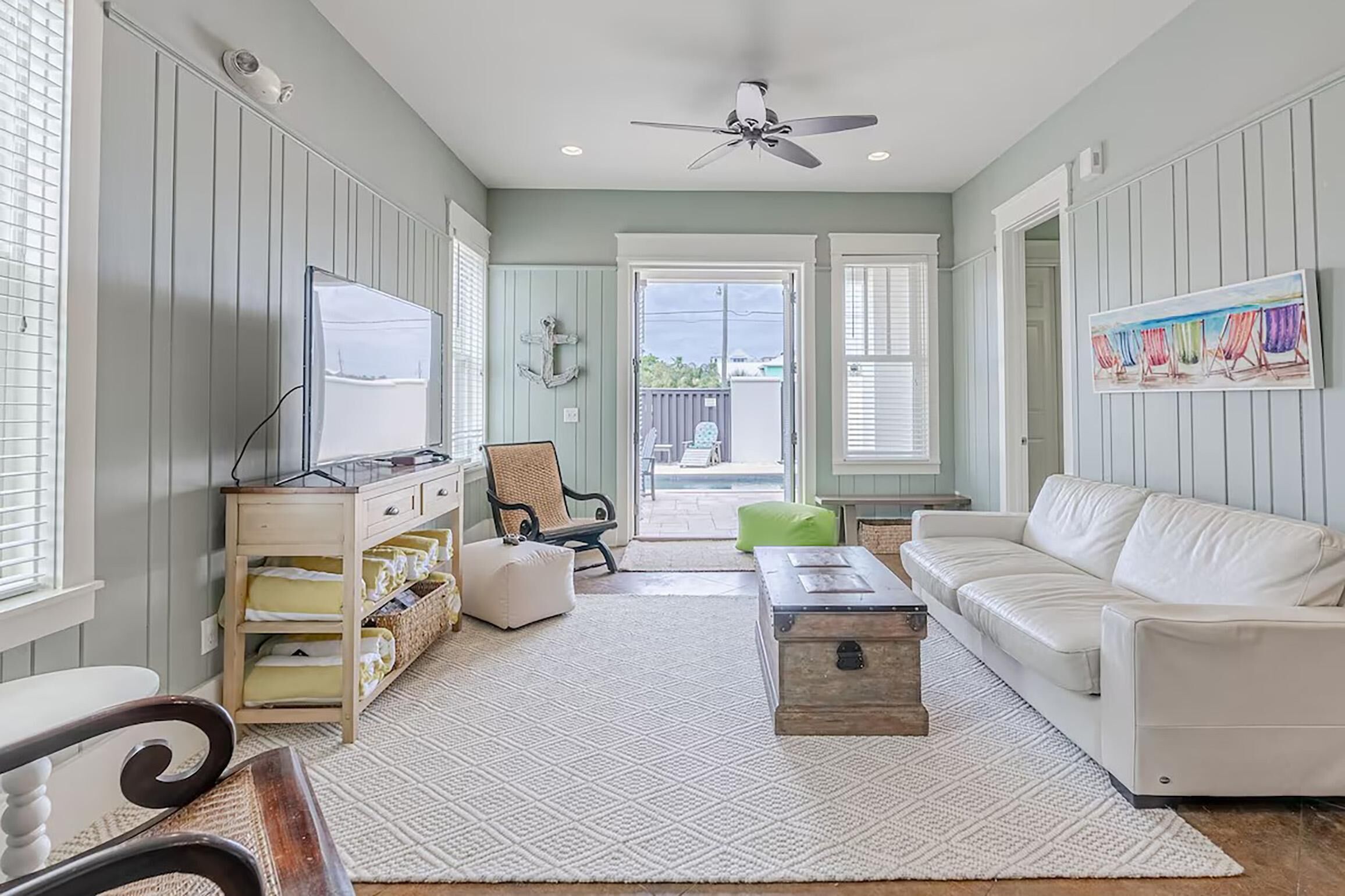 A living room with a white sofa, a coffee table, a TV, and a bookshelf.