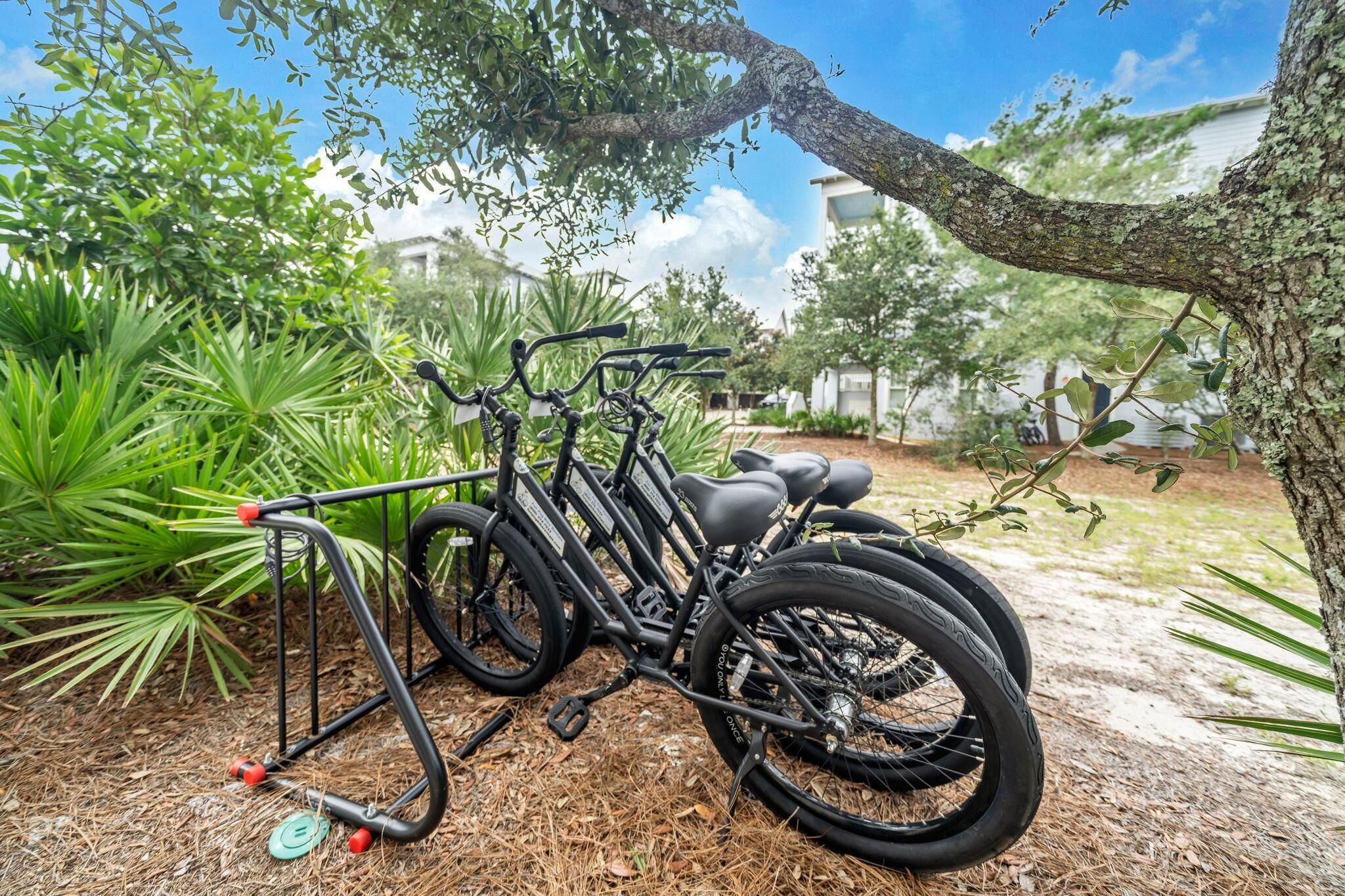 A bicycle parked on a rack in a garden with trees and a building in the background.