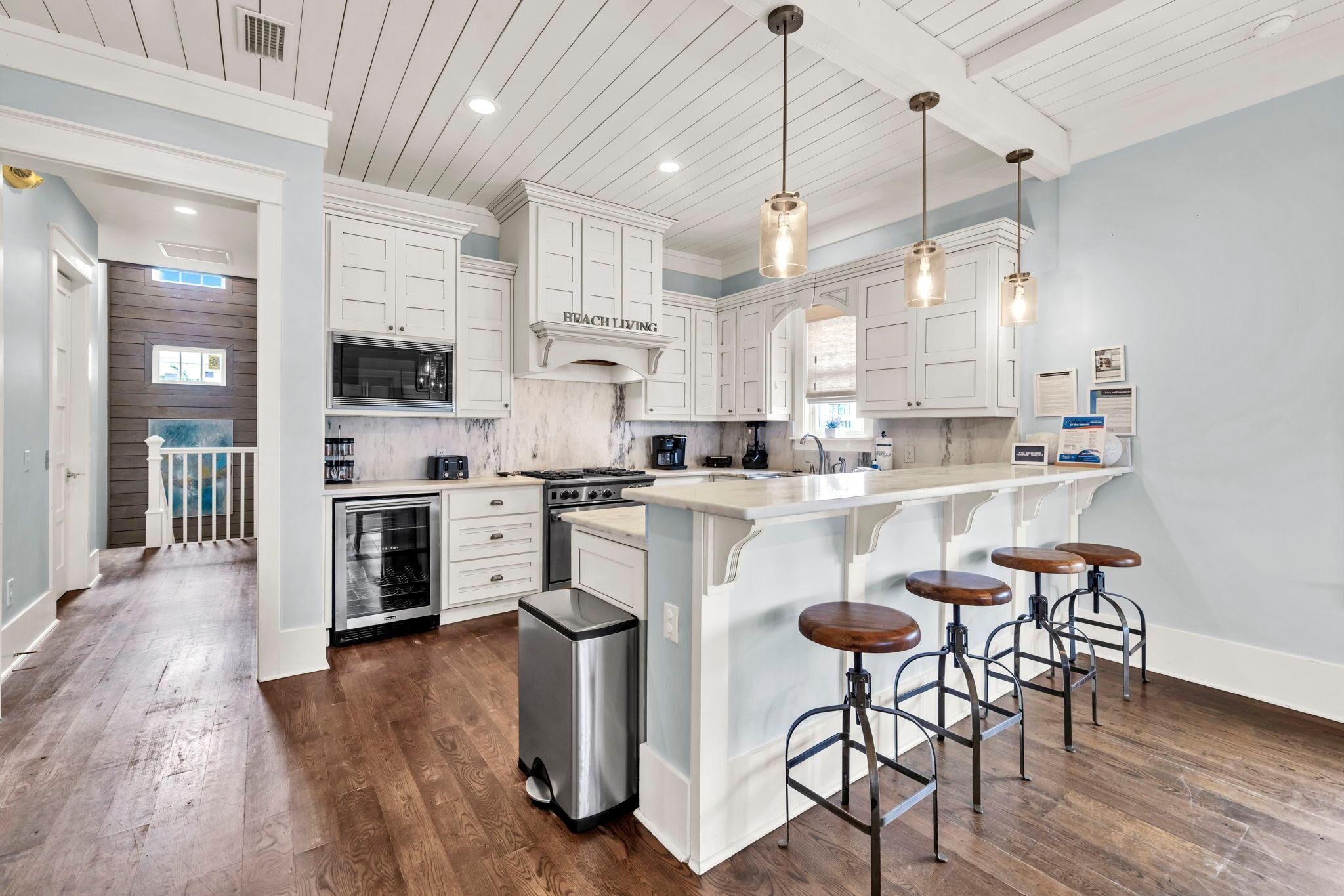 Una cocina amplia con muebles blancos, una isla grande con taburetes y vistas al patio trasero.